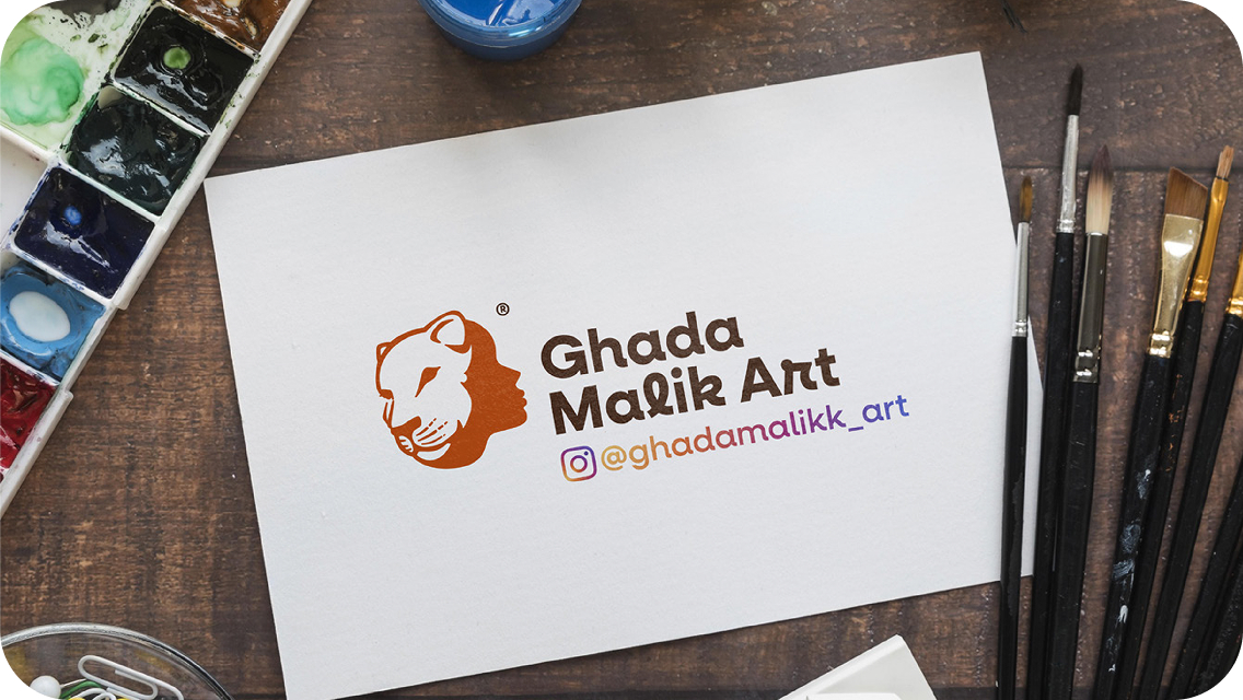 Ghada Malik Art logo on paper next to paintbrushes
